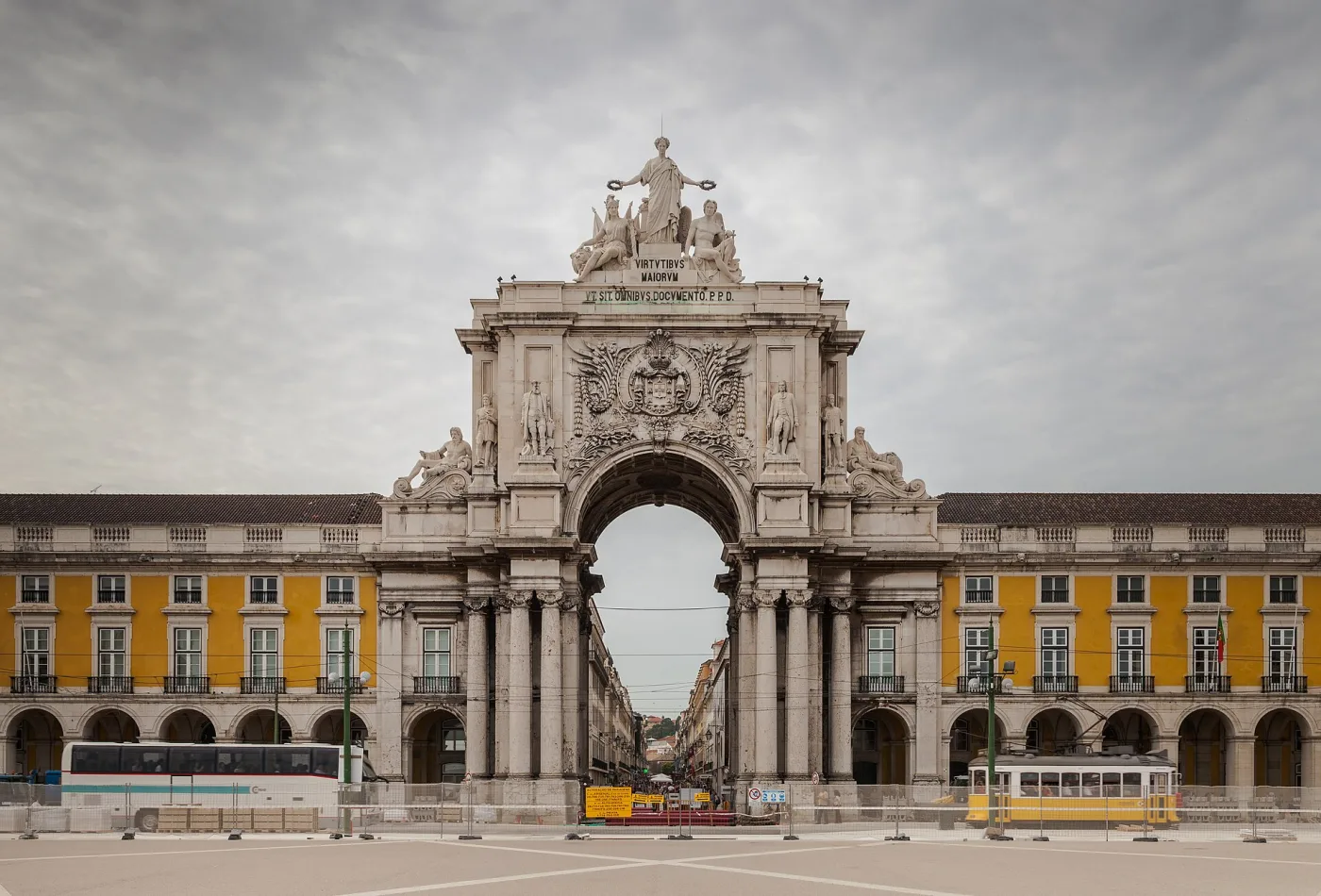 Arc de la Rua Augusta entre les façades jaunes de la Praça do Comércio, avec un tramway au premier plan