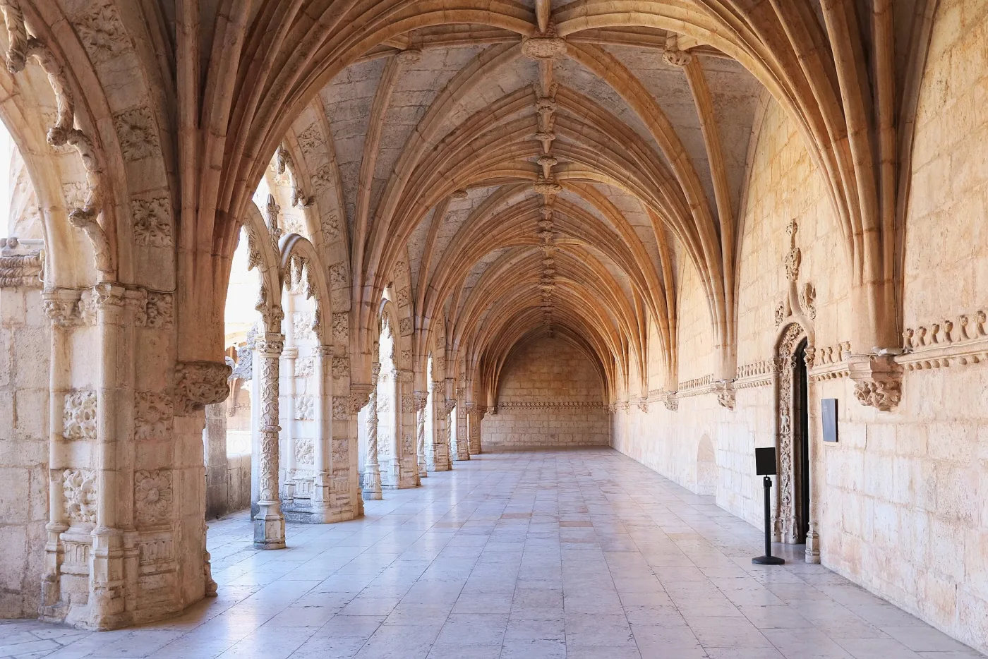 Galerie du cloître des Jerónimos, avec piliers sculptés, voûtes nervurées et sol de pierre claire